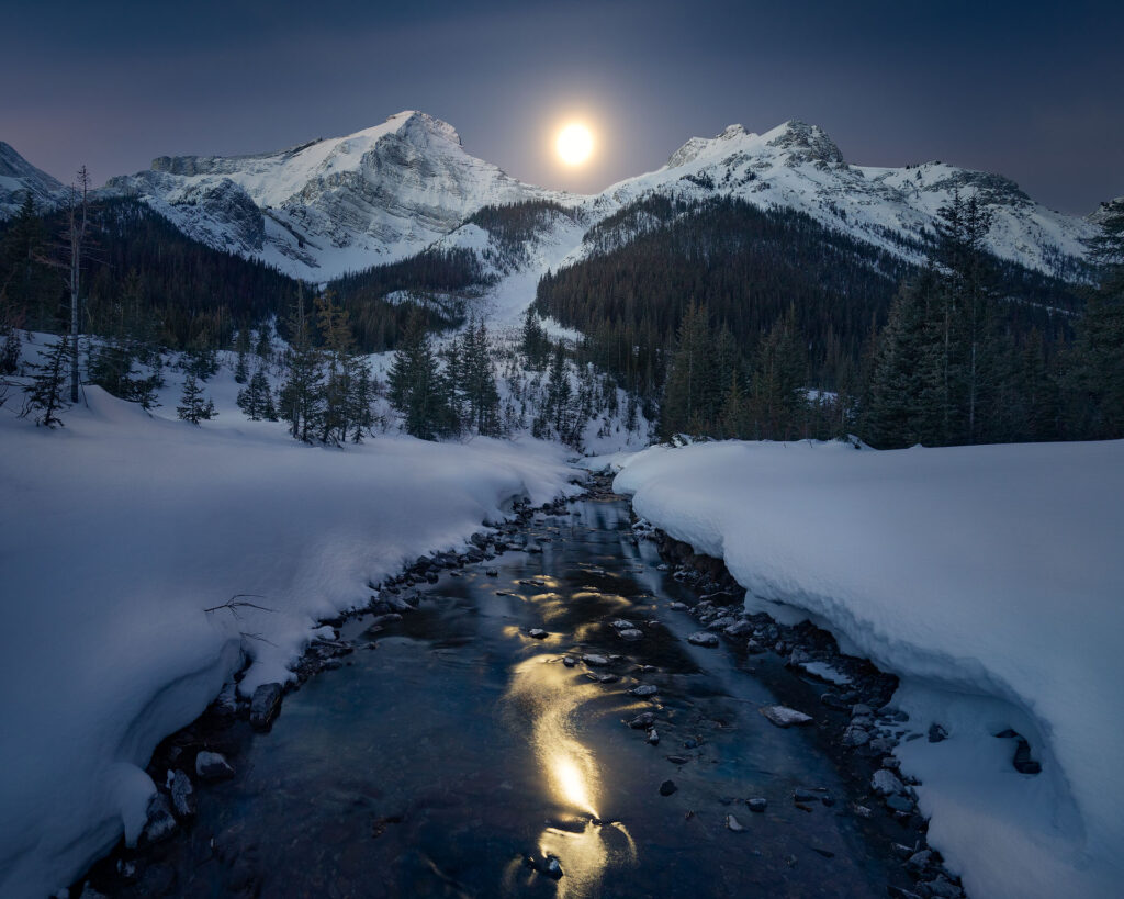 Moonset over snowy mountain river