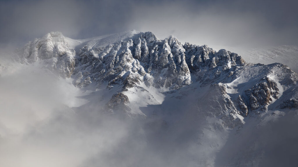 Snowy mountains breaking through clouds