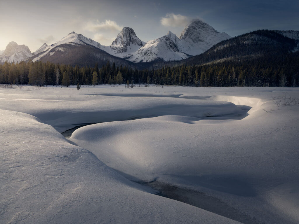 curves in snow lead up to dramatic winter mountain peaks