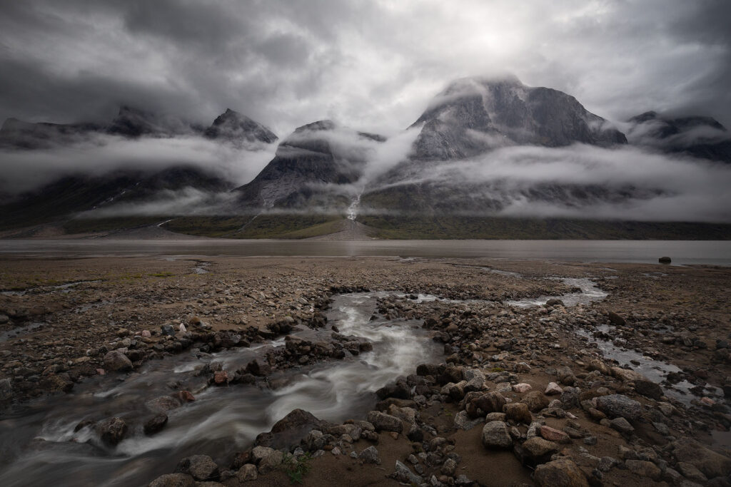 Cloud breaks through arctic mountain peaks over a small winding stream