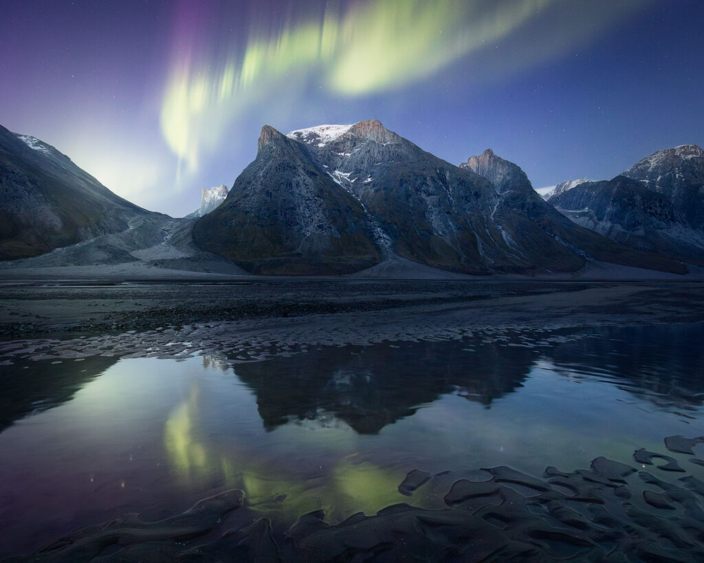 Aurora dances over arctic mountain peaks