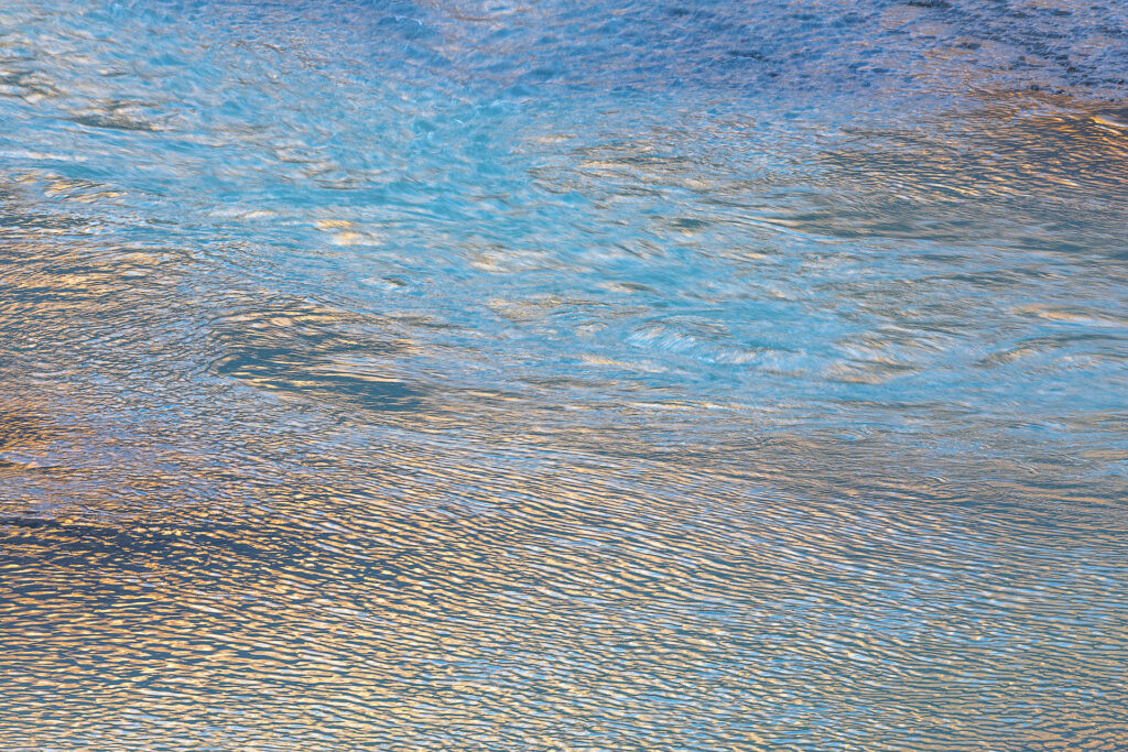 Shimmering water reflecting light from the sky and near-by mountains