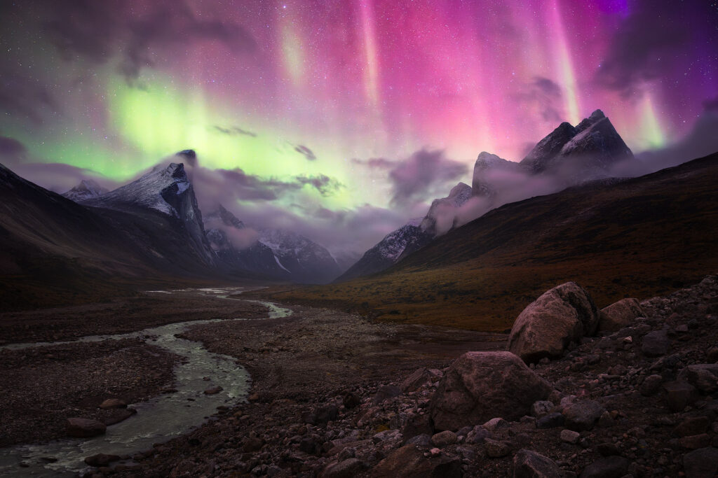 bright aurora dances over arctic mountain peaks on Baffin Island